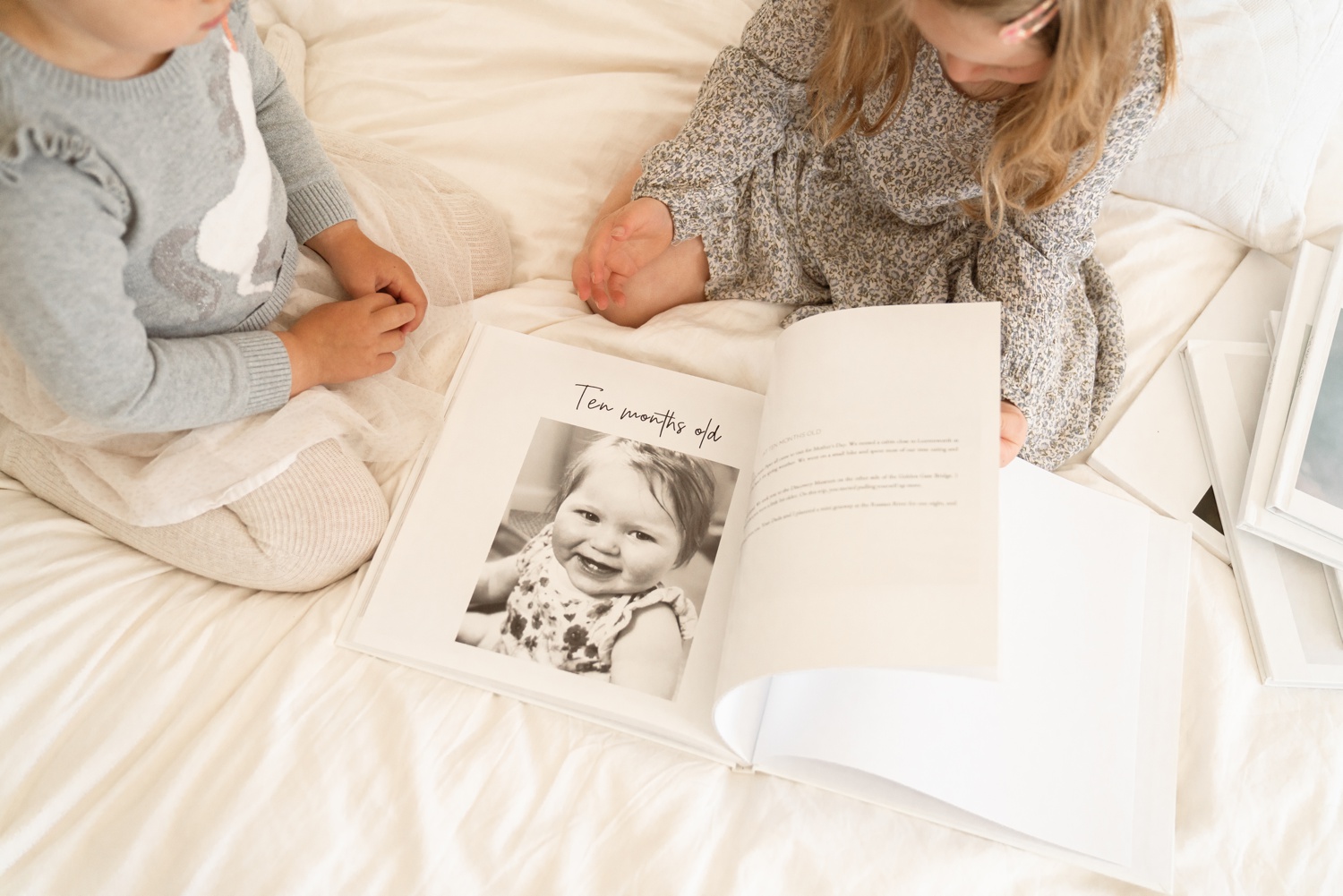 Two children flip through a modern baby book made with the Baby Notebook app.