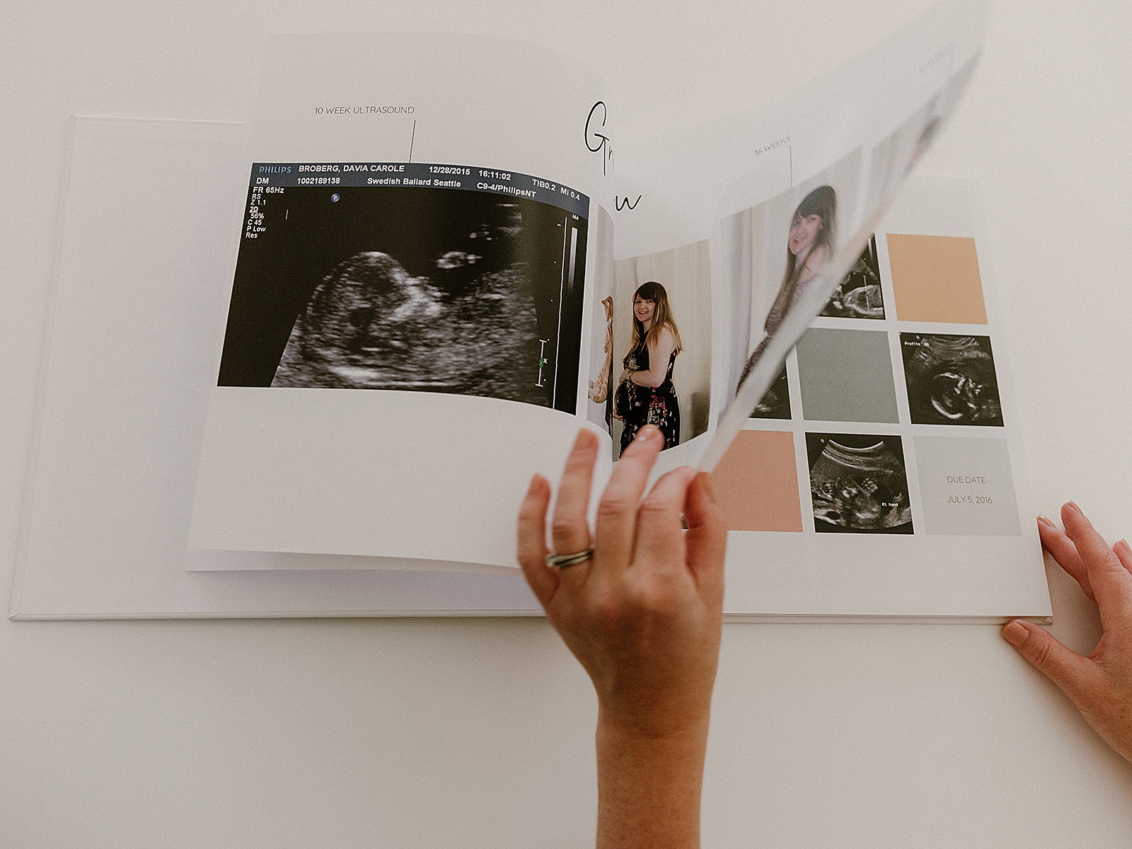 A woman opens a pregnancy journal to a pregnancy milestones page.