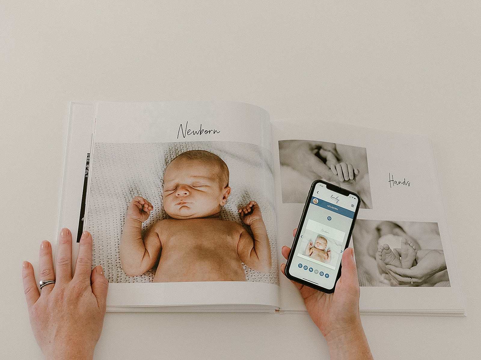 A woman holds a phone with a keepsake app beside a custom baby book.