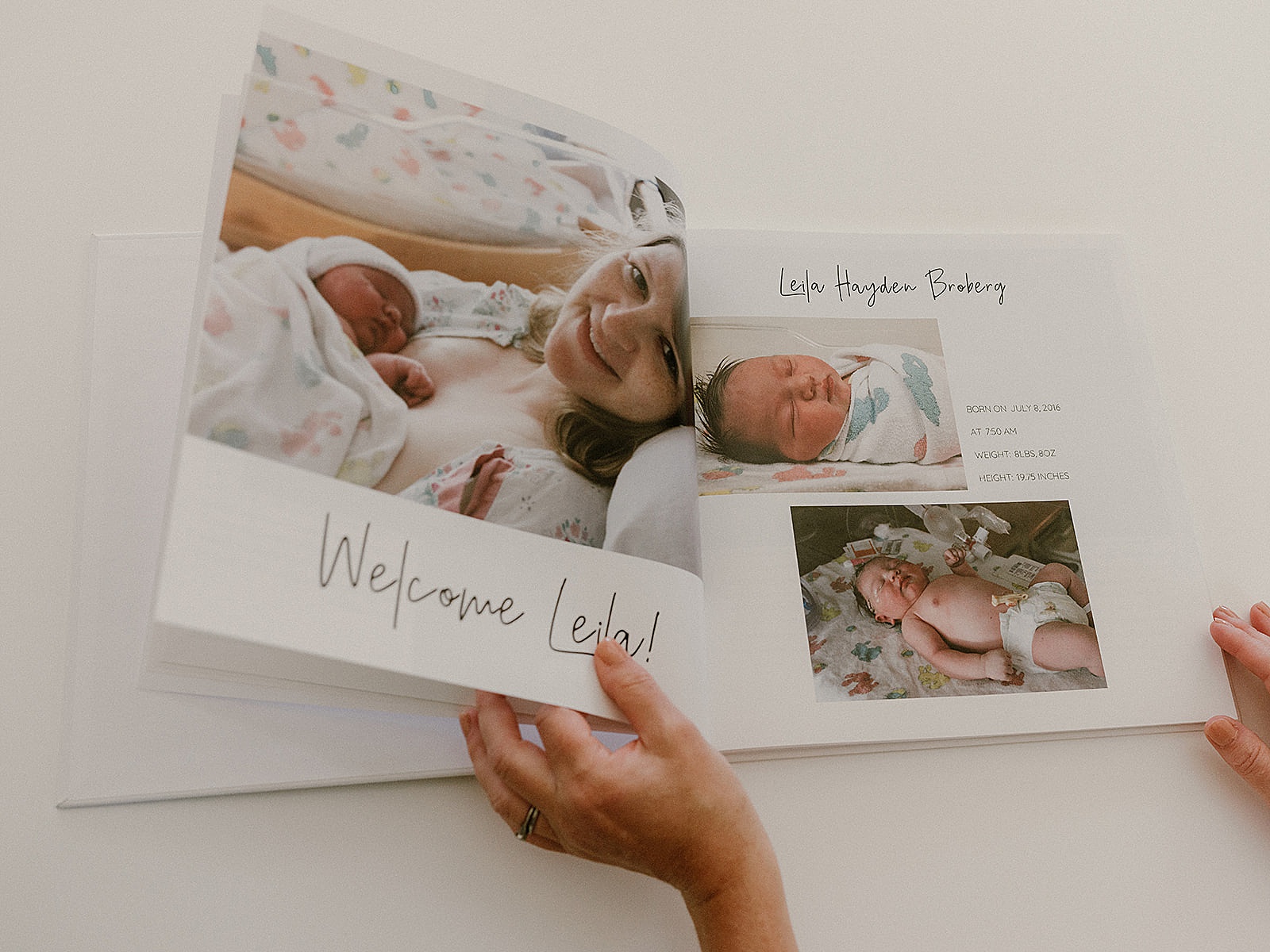 A woman flips through personalized baby books with Fresh 48 photos.