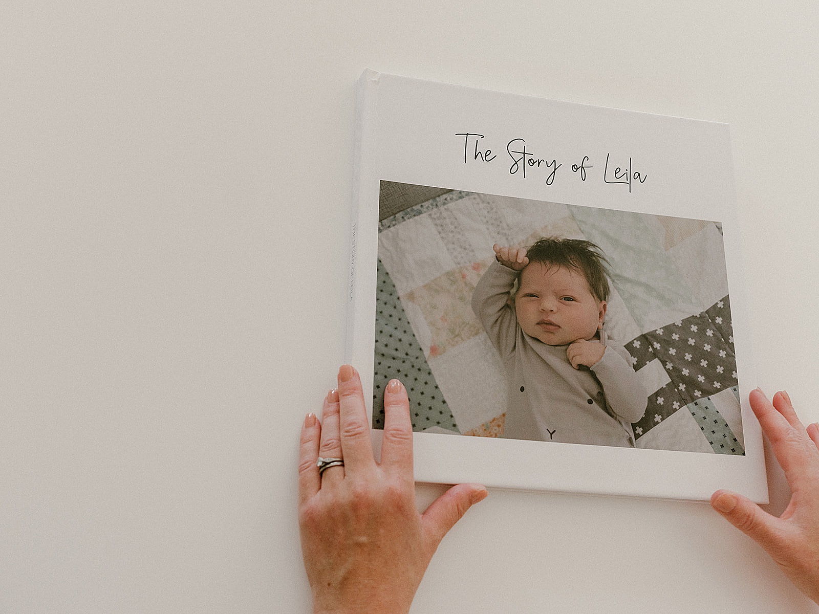 A woman holds a personalized baby book with a baby's photo on the front.