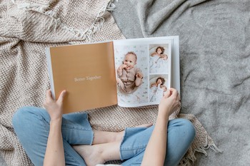A mom flips through a baby book created with memory book ideas.